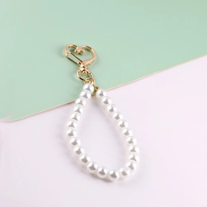 Close-up of golden heart lobster clasp with white faux pearl beaded handle strap