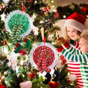 Detail of red and green striped Christmas elf leg hanging ornaments on a festive tree