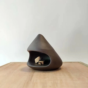 Detail of dark brown ceramic Palo Santo holder with natural wood pieces on wooden table