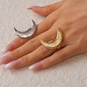 Artistic hammered metal moon ring set in gold and silver finish on a female hand