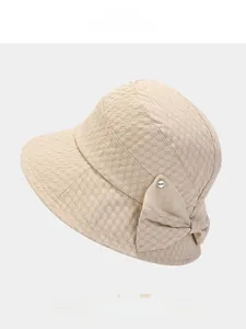 Detail of beige bucket hat showing textured bubble fabric and elegant mesh bow accent