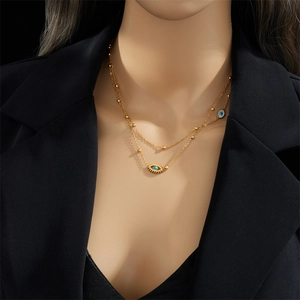 Double-layered gold necklace with blue Evil Eye and Hamsa Hand charms on black background
