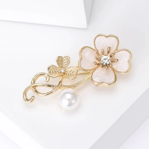 Detail of elegant pink enamel flower brooch with golden leaves and white pearl drop