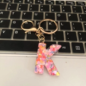Detail of letter K keychain with colorful heart sequins on a black laptop keyboard