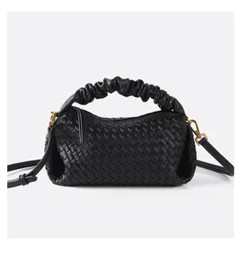 Close-up of black woven leather handbag featuring pleated handle and vintage gold buckles