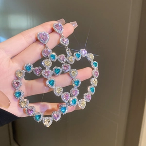Vue détaillée des boucles d'oreilles cœur évidées avec des strass colorés étincelants