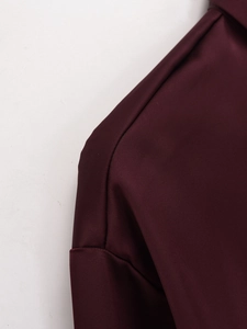 Macro shot of deep burgundy satin fabric texture and premium shoulder stitching details