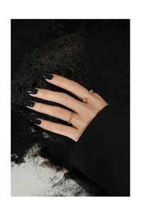 Artistic detail of gold knot rings worn against black rock background for a modern style