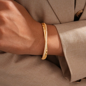 Detailed view of an 18k gold plated bangle with a pavé zircon intertwined design
