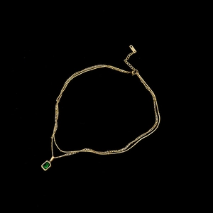 Détail de la chaîne double dorée avec pendentif émeraude et étiquette gravée S.STEEL