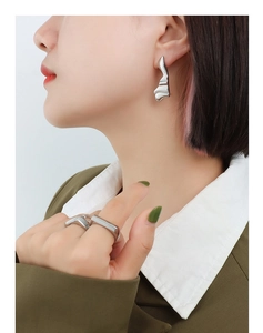 Détail de boucles d'oreilles vagues et bagues géométriques au fini miroir poli