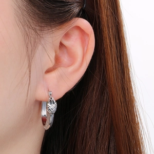 Detailed macro shot of silver snake head hoop earring with metal scale texture