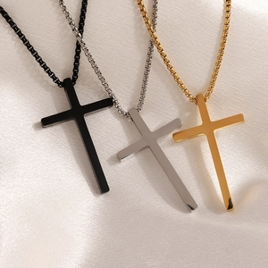 Detailed view of cross pendant necklaces in black, silver, and gold on soft fabric