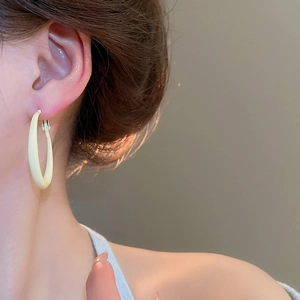 Close-up of minimalist cream round hoop earring worn on model for an elegant look