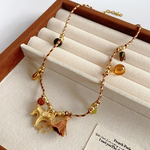 Detailed view of woven horse pendant necklace with amber beads in velvet box