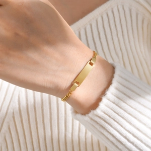 Close-up of a gold stainless steel ID bracelet with a blank bar on a woman's wrist