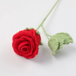 Close-up of a handmade red crochet rose bouquet with soft yarn texture and green leaf detail