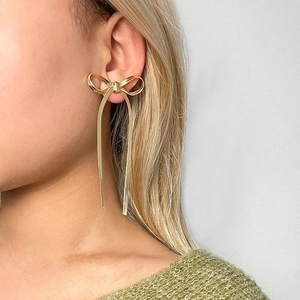 18K gold plated bow earrings with long snake chain tassels on a minimalist model