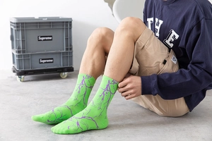 Détail de chaussettes vert fluo avec motif éclair violet et étiquette de marque