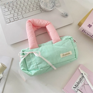 Detail of mint green quilted fabric bag with pink bow and thick padded handle