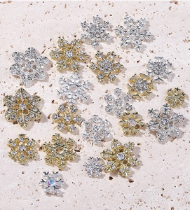 Close-up of gold and silver alloy snowflake nail charms with AB rhinestones on stone
