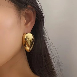 Polished 18k gold water drop earrings with liquid metal texture on a female model