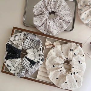 Detailed view of assorted floral and polka dot cotton hair scrunchies in a vintage tray