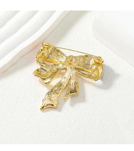 Detailed view of the golden metal bow brooch back showing fine texture and needle buckle