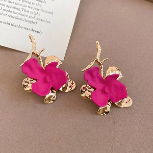 Macro view of orchid earrings with magenta matte petals and golden branch accents