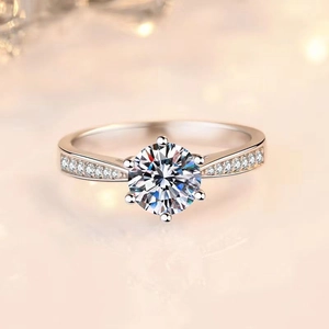 Detail of a six-prong solitaire ring with brilliant round cut stone and side accent diamonds