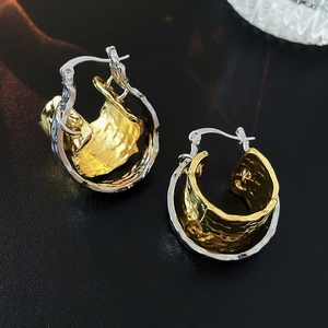 Detail of two-tone metal hoop earrings with silver outer and wrinkled gold inner ring