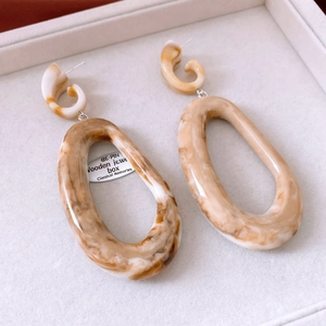 Detail of amber and cream marble resin oval earrings on a jewelry display tray
