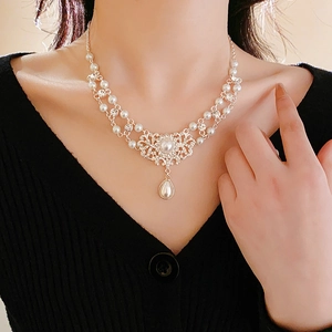 Detail der Vintage-Perlenkette mit glitzernden Strasssteinen und hohlem Blumenanhänger