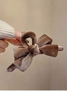 Detail of a large brown velvet bow hair claw clip showing soft texture and premium finish