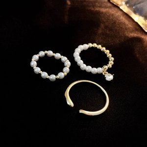 Detailed view of 3-piece gold-plated ring set with pearls and zircons on brown velvet