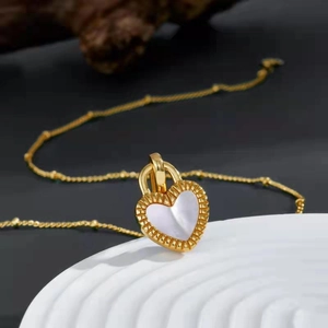 Macro shot of heart pendant with white shell inlay and gold gear edge on chain