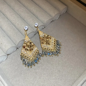 Detail of vintage gold diamond earrings with blue bead tassels on grey velvet background