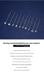 Detailed view of S999 silver letter ear threader earrings on a textured blue background
