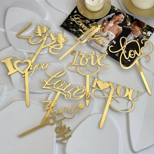 Detail of mirror gold acrylic Love cake toppers featuring romantic silhouettes and birds