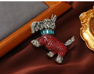 Macro shot of a vintage Scottish Terrier brooch with red and white crystals on silk