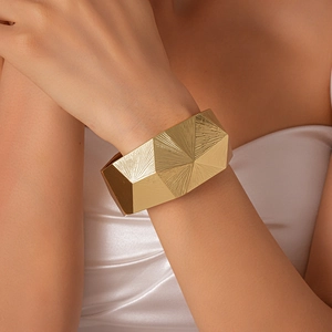 Close-up of golden wide open bangle with geometric faceted texture on female wrist