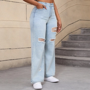 Dettaglio dei jeans a zampa d'elefante azzurri con ginocchia strappate e vita alta trendy