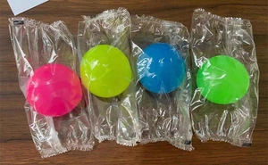 Vue détaillée de quatre balles collantes lumineuses colorées sous emballage plastique