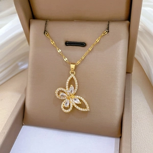 Detailed macro of a gold hollow butterfly pendant necklace with inlaid zircons on silk