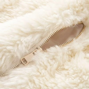 Close-up of soft white fuzzy texture and premium gold metal zipper on jacket