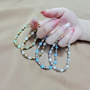 Elastic beaded bracelet set with cat eye stones and metallic faceted spacers on hand