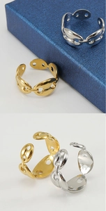 Detalle de los anillos con eslabones de café en oro y plata sobre joyero azul marino