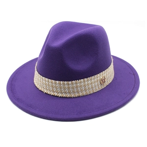 Detail of purple wool fedora featuring a beige braided band and golden M letter charm