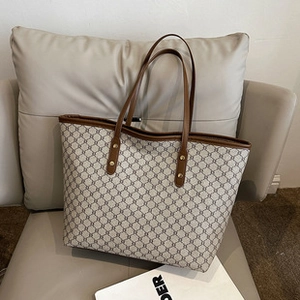 Detailed view of tote bag with brown geometric pattern on beige canvas and leather trim