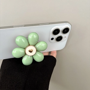 Detail of mint green floral phone grip with a gold heart center on a white smartphone
